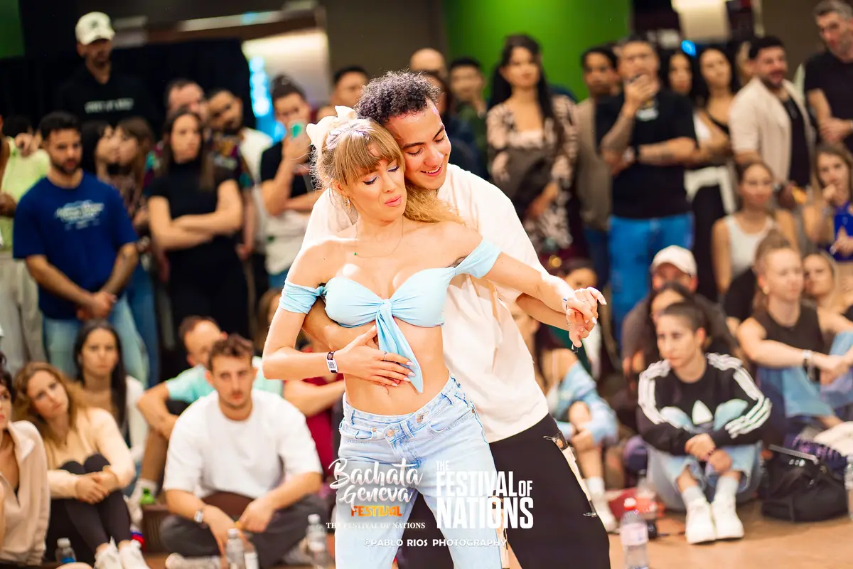 A couple laughing in an embrace while the other competitors watch from the floor